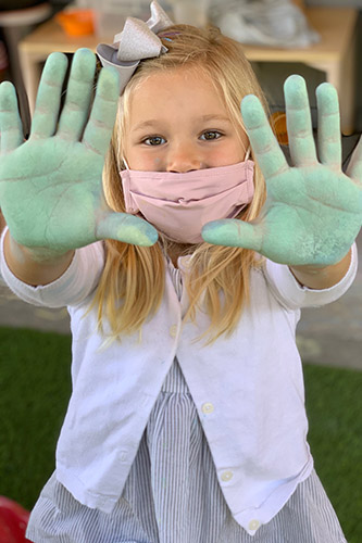 girl holding up her painted hands