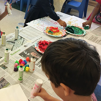 four children painting with dot paint and stamps