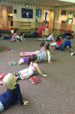several children on the floor doing a yoga pose in Litty Yogis class