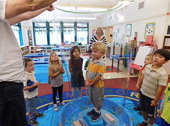 science class with a boy standing inside a bubble and other children watching