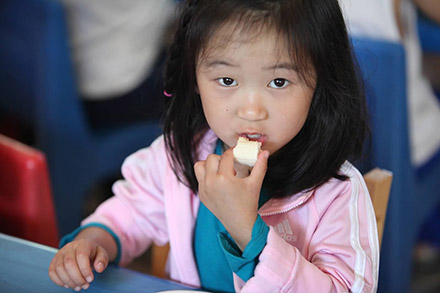 preschool girl eating lunch at a table