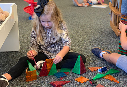 girl sitting on the floor building with magnatiles toys